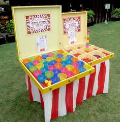 an open box filled with plastic cups on top of a grass covered field next to a table