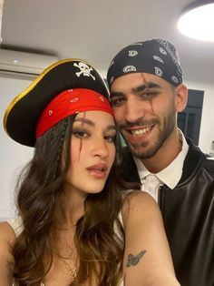 a man and woman pose for the camera wearing pirate hats with tattoos on their foreheads