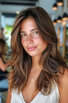 Woman with long, wavy brown hair and a slight smile, inside a modern, well-lit room. Brown Hair Highlights, Hair Color For Brown Eyes