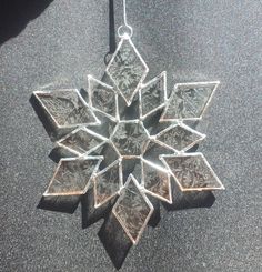 a silver snowflake hanging from a black cord