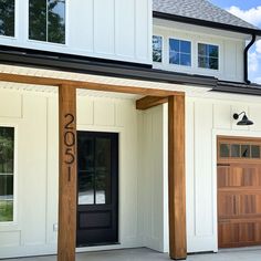 the front entrance to a white house with two garage doors and an open entryway