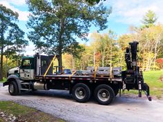 a large truck parked on the side of a road next to a tree filled forest