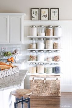 a kitchen with white cabinets and shelves filled with lots of different types of food items