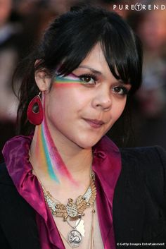 a woman with multicolored makeup and jewelry on her face