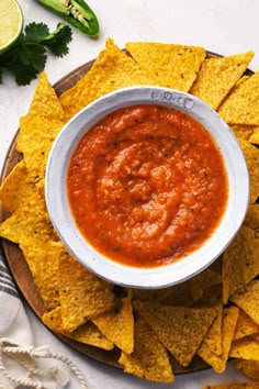 a white bowl filled with salsa surrounded by tortilla chips