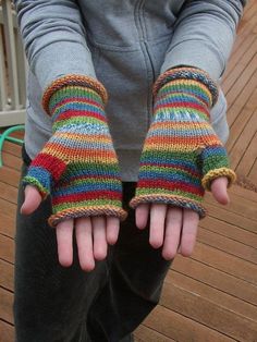 a person with their hands in knitted mitts on the decking area outside