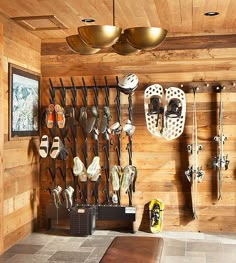 there are many skis and snowboards hanging on the wall in this room with wood paneling