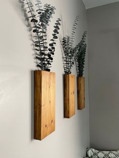 two wooden vases with plants in them on the wall next to a bed and pillow