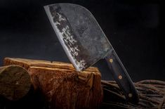 a large knife sitting on top of a piece of wood next to a tree stump