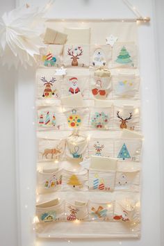 a white wall hanging with christmas decorations on it's sides and lights in the background