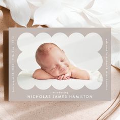 a birth announcement with a photo of a baby sleeping on it's side and white flowers in the background