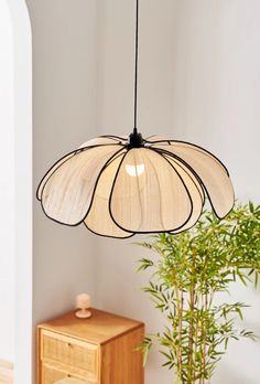 a light fixture hanging from the ceiling in a room with a potted plant next to it