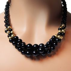 Presented by EclecticVintagerBlack Bead Necklace with a bit of panache !~ this black beaded necklace has small twisted strands of beads and the centerpiece has  loosely twisted three strands ag black and gold beads. This unique black beaded necklace is a stunning piece of vintage jewelry that combines twisted tiny beads with three strands of large chunky beads. The contrast between the delicate and bold elements creates a striking look that is sure to make a statement. Perfect for adding a touch of elegance to any outfit, this necklace is a must-have for any jewelry collection. The closure is a slide that slides into a large bead Approximate measurements: 18 inches by about 3/4 inch centerpiece Hallmark - unsigned Material - hard lucite More vintage necklaces in my shop - https://www.etsy. Black Beaded Necklace, Large Beads, Tiny Beads, Enamel Bangle, Beaded Jewelry Designs, Black Bead Necklace, Small Beads, Vintage Necklaces, Chunky Beads