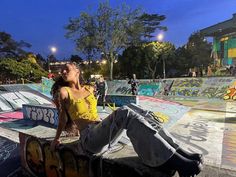 a woman sitting on top of a skateboard ramp in a park with graffiti all over the walls