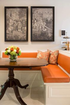 an orange bench sits in the center of a room with two paintings on the wall