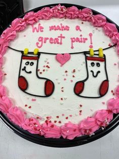 a birthday cake with pink frosting and two stockings on the side that says we make a great pair