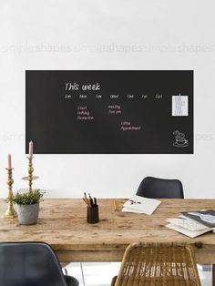 a wooden table topped with black chairs next to a chalkboard that says this week