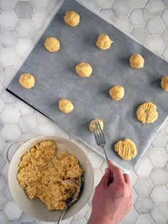 a person holding a fork near a bowl of food on a table with cookie balls