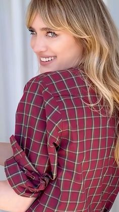 a woman with long blonde hair wearing a red plaid shirt and smiling at the camera