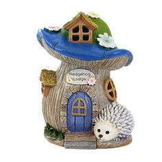 a ceramic hedgehog house with a blue roof and white flowers on the front door