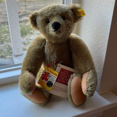 a brown teddy bear sitting on top of a window sill