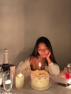 a woman sitting at a table with a cake and wine