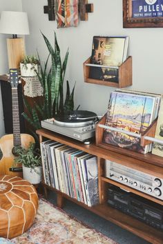 a record player sitting on top of a wooden shelf next to a plant and records