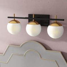 three lights are mounted on the wall above a mirror in a room with pink walls