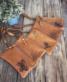 three brown leather purses sitting on top of a wooden table next to a potted plant