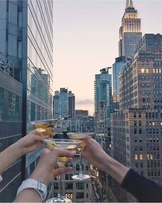 several people toasting with drinks in front of skyscrapers