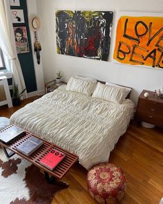 a bed sitting on top of a hard wood floor next to a table with books