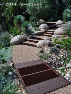 an outdoor area with rocks, plants and steps leading up to the top of it