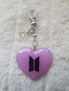 a pink heart shaped keychain with an arrow on it's front end