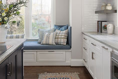 a kitchen with a window seat and rug on the floor next to the counter top