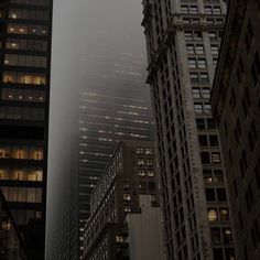 the skyscrapers are all lit up at night in the foggy cityscape