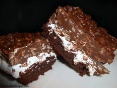 two pieces of chocolate cake with white frosting and brownie toppings on a plate