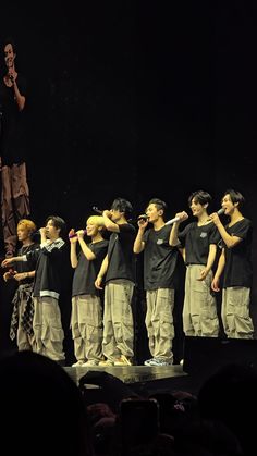 a group of young men standing on top of a stage next to eachother