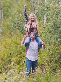 a man carrying a woman on his back through the woods