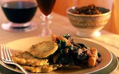 a white plate topped with food next to two glasses of wine