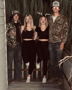 four people are standing on the steps in front of a house with deer antlers