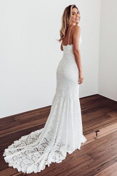 a woman in a white wedding dress standing on a wooden floor with her back to the camera