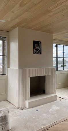 an empty living room with a fireplace and large windows