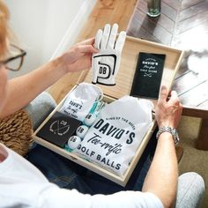 a woman holding up a box with some items in it and a pair of white gloves