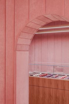 a display case with donuts inside of it in a pink wallpapered room