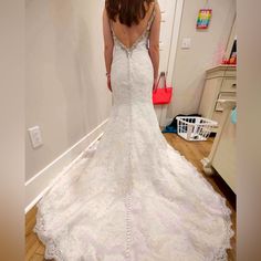 a woman in a wedding dress looking at herself in the mirror with her back to the camera