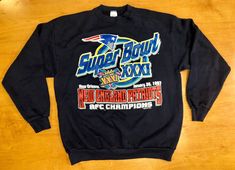 a black sweatshirt with the super bowl xxxii logo on it is laying on a wooden surface