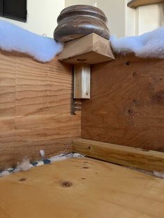 a birdhouse with snow on the roof and wood paneling around it's edges