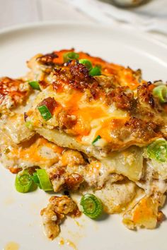 a white plate topped with lasagna covered in cheese and green pepper toppings