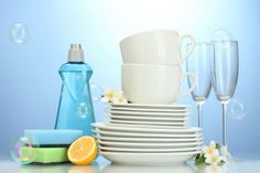 a stack of plates, cups and glasses with soap bubbles in the air next to them