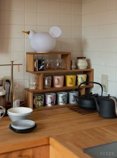 a kitchen counter with tea kettles and cups on it's shelf next to the stove